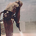 Worker sandblasting wearing full coverage protective gear. By National Institute for Occupational Safety and Health.